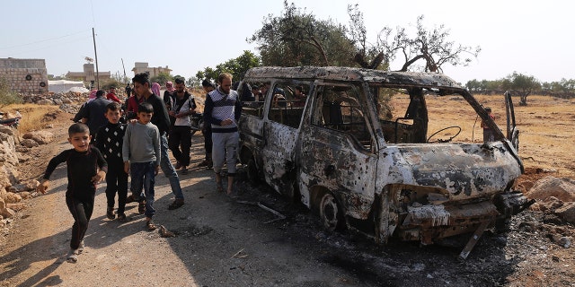 People look at a destroyed van near the village of Barisha, in Idlib province, Syria, Sunday, Oct. 27, 2019, after an operation by the U.S. military which targeted Abu Bakr al-Baghdadi, the shadowy leader of the Islamic State group. (AP Photo/ Ghaith Alsayed)