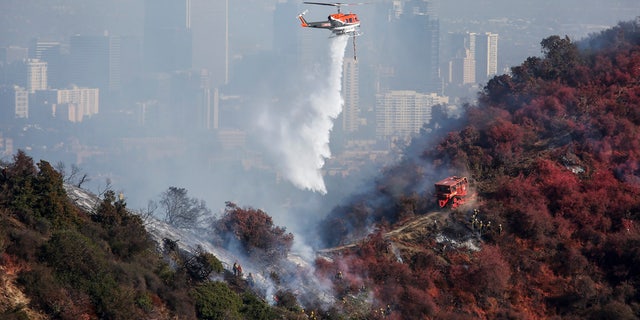 A helicopter drops water as a wildfire called the Getty Fire burns on Kenter Canyon in Los Angeles, Monday, Oct. 28, 2019.