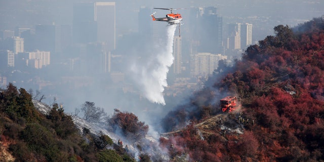 A helicopter drops water as a wildfire called the Getty Fire burns on Kenter Canyon in Los Angeles, Monday, Oct. 28, 2019.