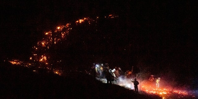 Firefighters work to douse a flare-up as the Kincade Fire burns through a vineyard in Calistoga, Calif., on Tuesday, Oct. 29, 2019.