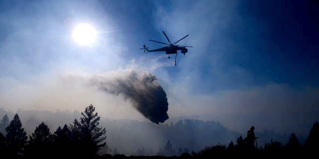 A helicopter drops water while battling the Kincade Fire near Healdsburg, Calif., on Tuesday, Oct. 29, 2019. Millions of people have been without power for days as fire crews race to contain two major wind-whipped blazes that have destroyed dozens of homes at both ends of the state: in Sonoma County wine country and in the hills of Los Angeles. (Associated Press)
