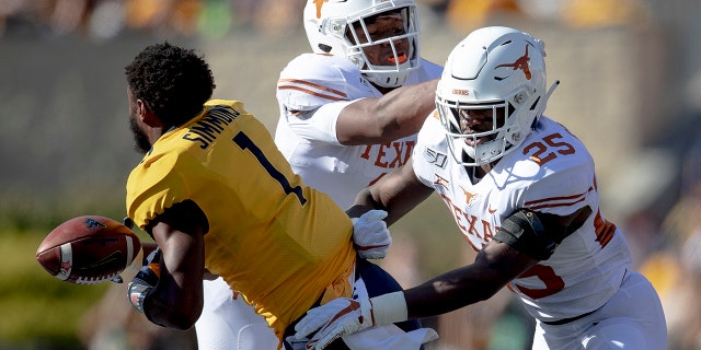 Texas defensive back B.J. Foster (25) shoves West Virginia wide receiver T.J. Simmons (1) during an NCAA college football game on Saturday, Oct. 5, 2019, in Morgantown, W.Va. (Nick Wagner/Austin American-Statesman via AP)
