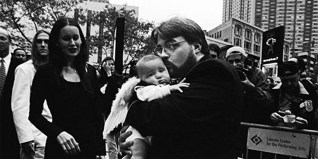 American director and screenwriter Kevin Smith holds daughter Harley Quinn dressed in angel wings on the red carpet at the premiere of this film