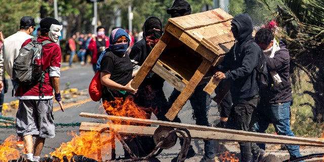 Demonstrators build a burning barricade during a protest in Santiago, Chile, Saturday, Oct. 19, 2019.