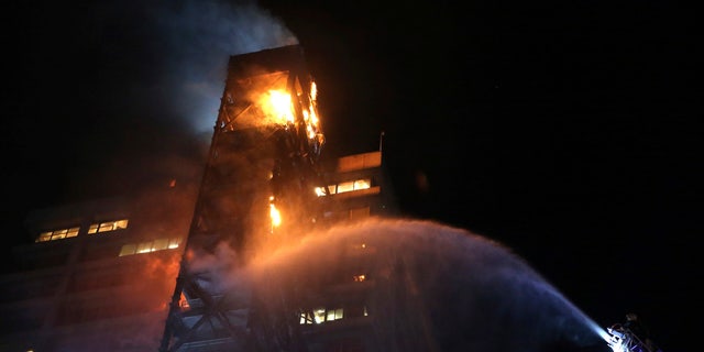 Firefighters work to put out the flames rising from the Enel Energy Europe building set on fire by protesters against the rising cost of subway and bus fares, in Santiago, Friday, Oct. 18, 2019.