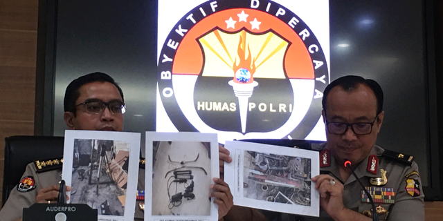 Indonesian National Police spokesperson Brig.Gen. Dedi Prasetyo, right, and an aide show photos of evidence of confiscated items during raids following a knife attack against Indonesian Coordinating Minister for Politics, Law and Security Wiranto during a press conference in Jakarta, Indonesia, Monday, Oct. 14, 2019. Prasetyo says tens of suspected militants plotting bombings and other attacks have been arrested in a new counterterrorism crackdown since last week's brazen assault by a knife-wielding militant couple who wounded the country's top security minister in a western province. (AP Photo/Niniek Karmini)