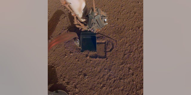 This October 2019 photo made available by NASA shows InSight's heat probe digging into the surface of Mars. On Thursday, Oct. 17, 2019, NASA says the drilling device has penetrated three-quarters of an inch (2 centimeters) over the past week, after hitting a snag seven months ago. While just a baby step, scientists are thrilled with the progress. (NASA/JPL-Caltech via AP)