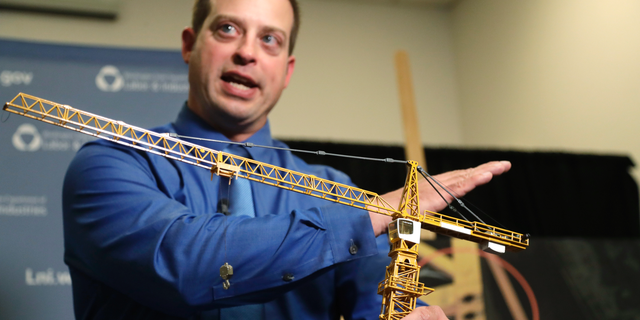 Brian Haight, crane program manager for Washington state's Department of Labor and Industries, uses a model of a crane during a news conference Thursday, Oct. 17, 2019, in Tukwila, Wash., to explain the collapse of a crane earlier in the year in Seattle that killed four. Washington State's L&I released the results of its investigation on the collapse Thursday. It found, as experts have long suspected, that the crane toppled because workers who were disassembling it had prematurely removed pins securing the sections of the crane's mast. (AP Photo/Elaine Thompson)