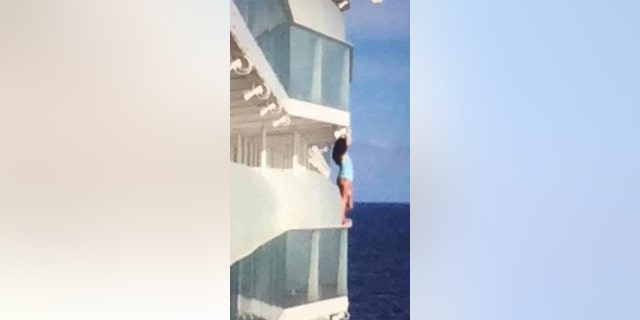 One Royal Caribbean cruise ship passenger, pictured, has been slammed as an “absolute idiot” for climbing over a balcony railing to take a swimsuit selfie, high above the ocean.