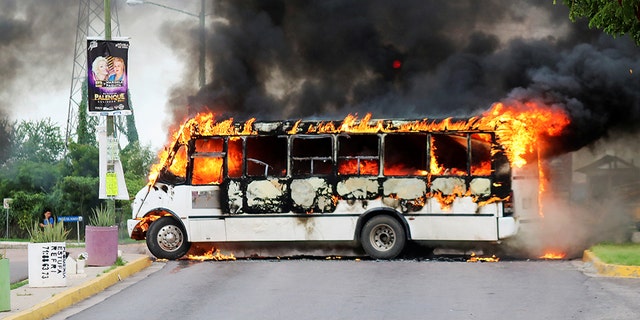 A burning bus, set alight by cartel gunmen to block a road, is pictured during clashes with federal forces following the detention of Ovidio Guzman, son of drug kingpin Joaquin 