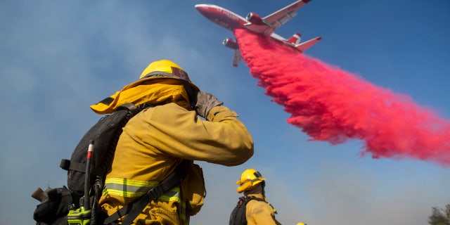 Firefighters brace themselves for incoming fire retardant during the Easy Fire, Wednesday, Oct. 30, 2019, in Simi Valley, Calif.