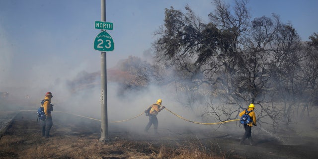 Firefighters put out hot spots along Highway 23, closed to traffic due to the Easy Fire, Wednesday, Oct. 30, 2019, in Simi Valley, Calif.