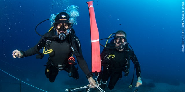 Divers lifting wooden pulley lifts from the wreck site.