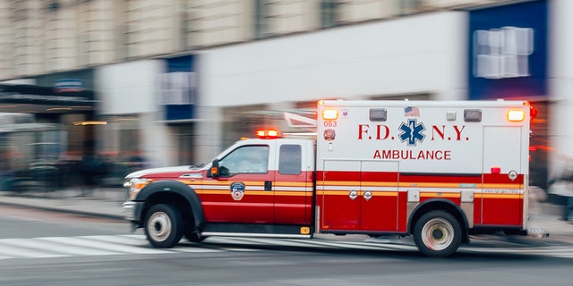 FDNY Ambulance flashing lights siren blasting speed through midtown rush hour traffic in Manhattan.