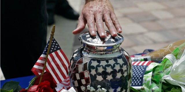 Mourners reach out an touch an urn holding the remains U.S. Army veteran Edward K. Pearson during an open funeral service Tuesday, Oct. 1, 2019, at the Sarasota National Cemetary in Sarasota, Fla.
