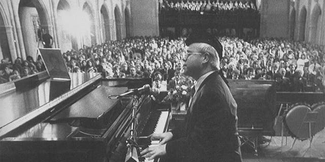 Singer Elton John playing piano and singing at the funeral of teenage AIDS victim Ryan White.