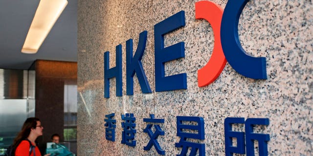 A woman walks past a logo of the Hong Kong Stock Exchanges in Hong Kong, Tuesday, Oct. 8, 2019. (AP Photo/Kin Cheung)