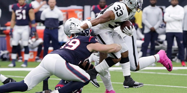 Oakland Raiders running back DeAndre Washington (33) is hit by Houston Texans defensive end J.J. Watt (99) on a run during the first half of an NFL football game Sunday, Oct. 27, 2019, in Houston. (AP Photo/Michael Wyke)