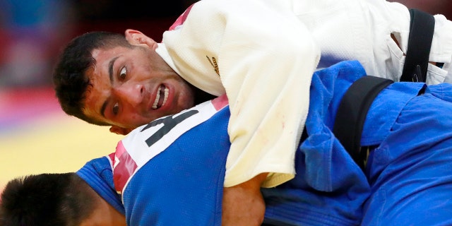 FILE - In this Thursday, Aug. 30, 2018 file photo, Saeid Mollaei of Iran, top, competes against Didar Khamza of Kazakhstan during their men's - 81kg final judo match at the18th Asian Games in Jakarta, Indonesia. Judo world champion Iran has been banned from international judo competitions for refusing to let its athletes fight Israeli opponents. The International Judo Federation has imposed an indefinite ban on Iran’s team until it promises to end a long-running boycott of Israel. (AP Photo/Tatan Syuflana, File)