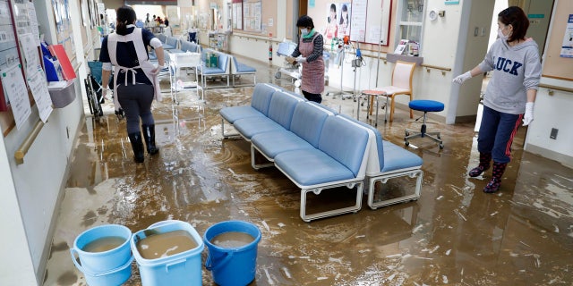 Staff members clean a hospital damaged by Typhoon Hagibis, in Marumori town, Miyagi prefecture, Japan Tuesday, Oct. 15, 2019.