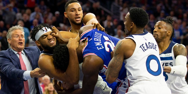 Joel Embiid #21 of the Philadelphia 76ers gets in a fight with Karl-Anthony Towns #32 of the Minnesota Timberwolves as head coach Brett Brown and Ben Simmons #25 of the Philadelphia 76ers try to break them apart along with Jeff Teague #0 and Robert Covington #33 of the Minnesota Timberwolves in the third quarter at the Wells Fargo Center on October 30, 2019 in Philadelphia, Pennsylvania.