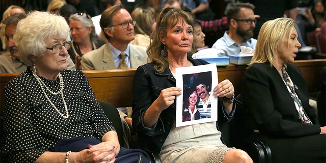 An attendee holds a photo of Cheri Domingo and her boyfriend Gregory Sanchez, who were killed in 1981, during DeAngelo's arraignment.