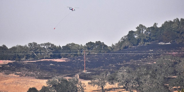 Helicopters drop water on hilltops as soldiers from the 49th Military Police Brigade operate traffic control points. (California National Guard)