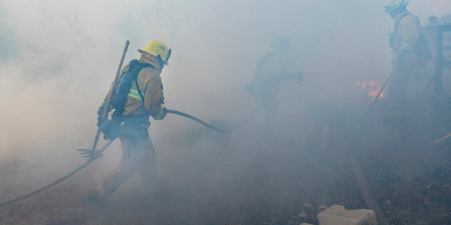 A firefighter from San Matteo pulls a hose line as crews work to suppress the Kincade Fire in Sonoma County, Calif., on Sunday, Oct. 27, 2019.