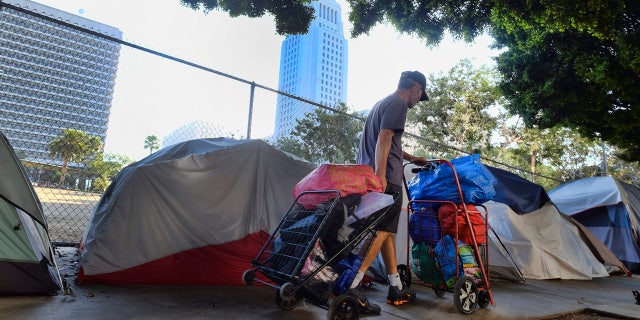 A homeless man moves his belongings from a street behind Los Angeles City Hall as crews prepared to clean the area on July 1, 2019.