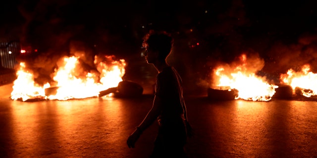 A Lebanese demonstrator walks past burning tires during the tax protest in a Beirut suburb. (Anwar Amro/AFP via Getty Images)