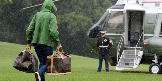 A White House aide carries Louis Vuitton bags to a helicopter prior to President Trump and first lady Melania Trump's departure from the White House on Sept. 2, 2017.