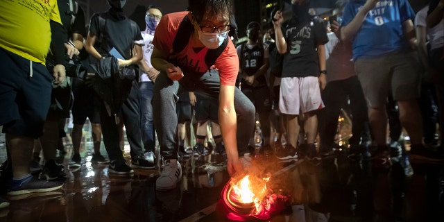 Demonstrators set a Lebron James jersey on fire during a rally at the Southorn Playground in Hong Kong, Tuesday, Oct. 15, 2019. (AP Photo/Mark Schiefelbein)