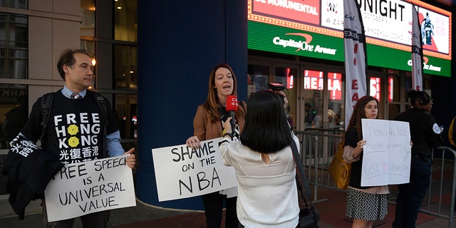 Activists hold signs outside Capital One Arena before an NBA preseason basketball game between the Washington Wizards and the Guangzhou Loong-Lions, Wednesday, Oct. 9, 2019, in Washington. (AP Photo/Nick Wass)