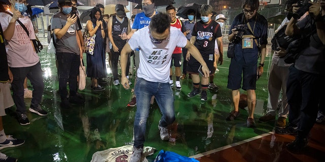 A demonstrator stomps on Lebron James jerseys during a rally at the Southorn Playground in Hong Kong, Tuesday, Oct. 15, 2019. (AP Photo/Mark Schiefelbein)