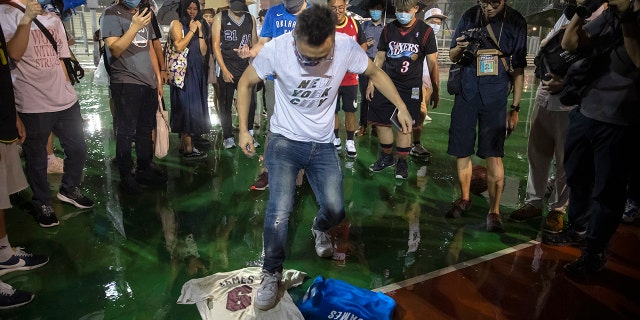 A demonstrator stomps on Lebron James jerseys during a rally at the Southorn Playground in Hong Kong, Tuesday, Oct. 15, 2019. (AP Photo/Mark Schiefelbein)