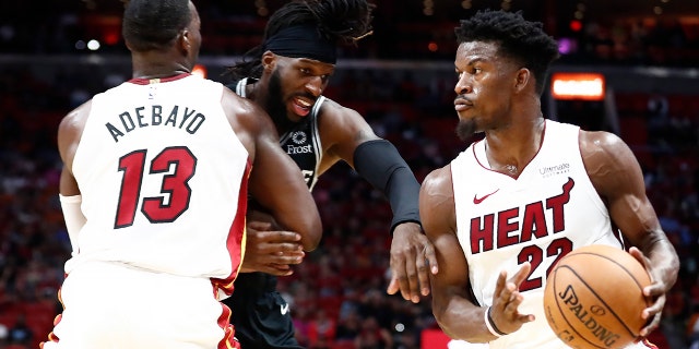 Miami Heat forward Jimmy Butler (22) dribbles the ball against San Antonio Spurs forward DeMarre Carroll (77) during the second half of an NBA preseason basketball game Tuesday, Oct. 8, 2019, in Miami. (AP Photo/Brynn Anderson)
