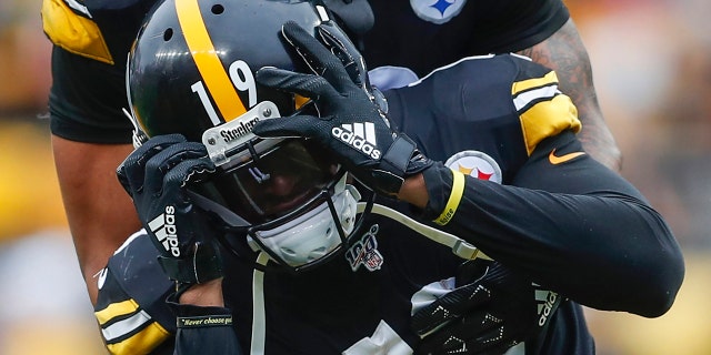 Pittsburgh Steelers running back James Conner (30) holds onto wide receiver JuJu Smith-Schuster (19) who reacts after quarterback Mason Rudolph (2) was injured in the second half of an NFL football game against the Baltimore Ravens, Sunday, Oct. 6, 2019, in Pittsburgh. (AP Photo/Don Wright)