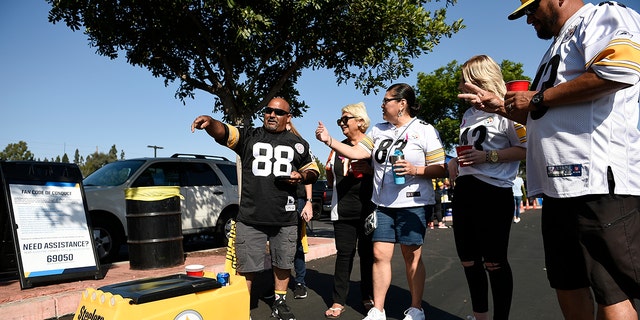 Fans stand in front of a remote controlled cooler prior to an NFL football game between the Pittsburgh Steelers and the Los Angeles Chargers, Sunday, Oct. 13, 2019, in Carson, Calif. (AP Photo/Kelvin Kuo)