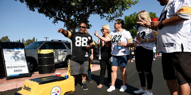 Fans stand in front of a remote controlled cooler prior to an NFL football game between the Pittsburgh Steelers and the Los Angeles Chargers, Sunday, Oct. 13, 2019, in Carson, Calif. (AP Photo/Kelvin Kuo)
