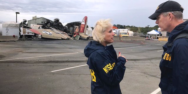 In this photo released via Twitter by the National Transportation Safety Board, NTSB board Member Jennifer Homendy, left, and investigator Dan Bower stand at the scene where a World War II-era bomber plane, left, crashed at Bradley International Airport in Windsor Locks, Conn., Wednesday, Oct. 2, 2019.