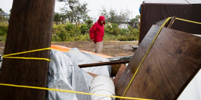 Chris Anderson ties down building materials and other objects from his lawn as Tropical Storm Nestor approached Mexico Beach, Fla..