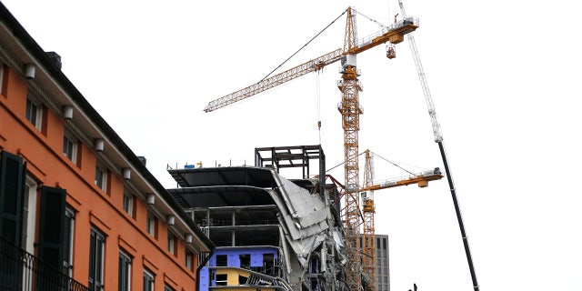 Workers in a bucket hoisted by a crane preparing the two unstable cranes for implosion at the collapse site of the Hard Rock Hotel n New Orleans on Friday.