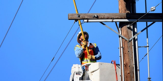 A Pacific Gas and Electric Co. crew trips a segment of power lines in Santa Rosa, Calif., Wednesday, Oct. 23, 2019, that will make it easier to restore power. The power was shut off due to the high fire danger. (Kent Porter/The Press Democrat via AP)