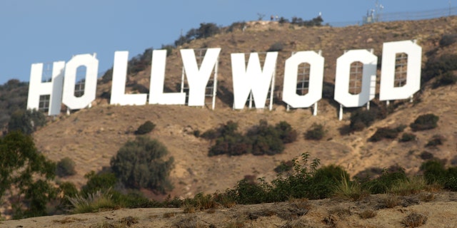 Hikers pass by the Hollywood sign in Hollywood, Los Angeles, California.