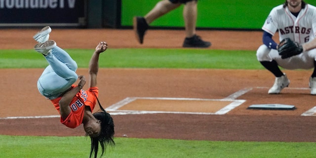 Gymnast Simone Biles does a flip before throwing the ceremonial first pitch before Game 2 of the baseball World Series between the Houston Astros and the Washington Nationals Wednesday, Oct. 23, 2019, in Houston. (AP Photo/Eric Gay)