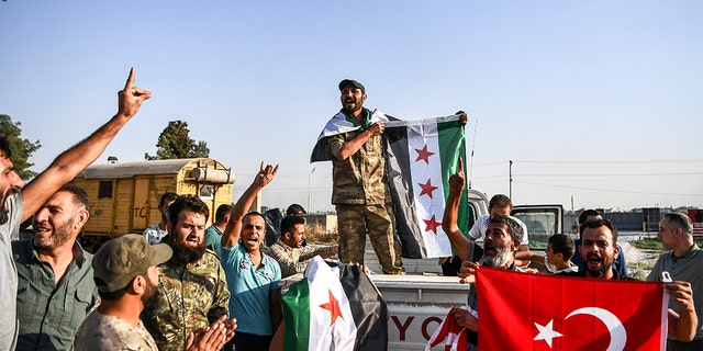 Turkish-backed Syrian opposition fighters celebrate in Akcakale, in Sanliurfa province advance, after entering over the border from Tal Abyad, Syria, Sunday, Oct. 13, 2019. State-run Anadolu news agency reported Tal Abyad had fallen to a Turkish military offensive on Sunday. (AP Photo/Cavit Ozgul)