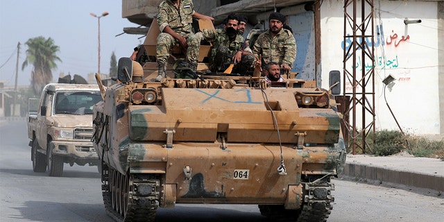 Turkey-backed Syrian rebel fighters ride on a military truck at the border town of Tel Abyad, Syria, on Monday. REUTERS/Khalil Ashawi - RC1A42D723C0