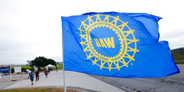 File- In this Sept. 30, 2019, file photo a UAW flag flies near strikers outside the General Motors Orion Assembly plant in Orion Township, Mich. (AP Photo/Paul Sancya, File)