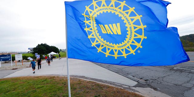File- In this Sept. 30, 2019, file photo a UAW flag flies near strikers outside the General Motors Orion Assembly plant in Orion Township, Mich. (AP Photo/Paul Sancya, File)