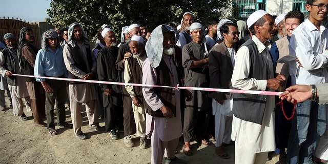 Men line up outside a polling station in western neighborhood of Kabul, Afghanistan, on Saturday. Afghans headed to the polls that day to elect a new president amid high security and threats of violence from Taliban militants, who warned citizens to stay away from polling stations or risk being hurt.
